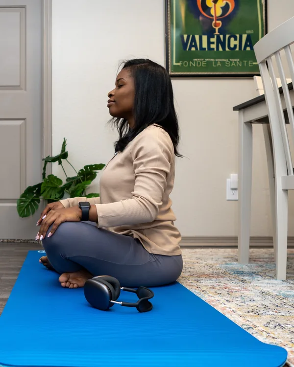Moment de respiration assise sur un tapis, à la maison, casque posé à côté.