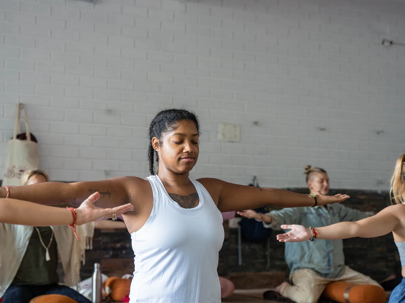 Atelier collectif dans une salle claire, une pratiquante bras ouverts au centre du groupe.